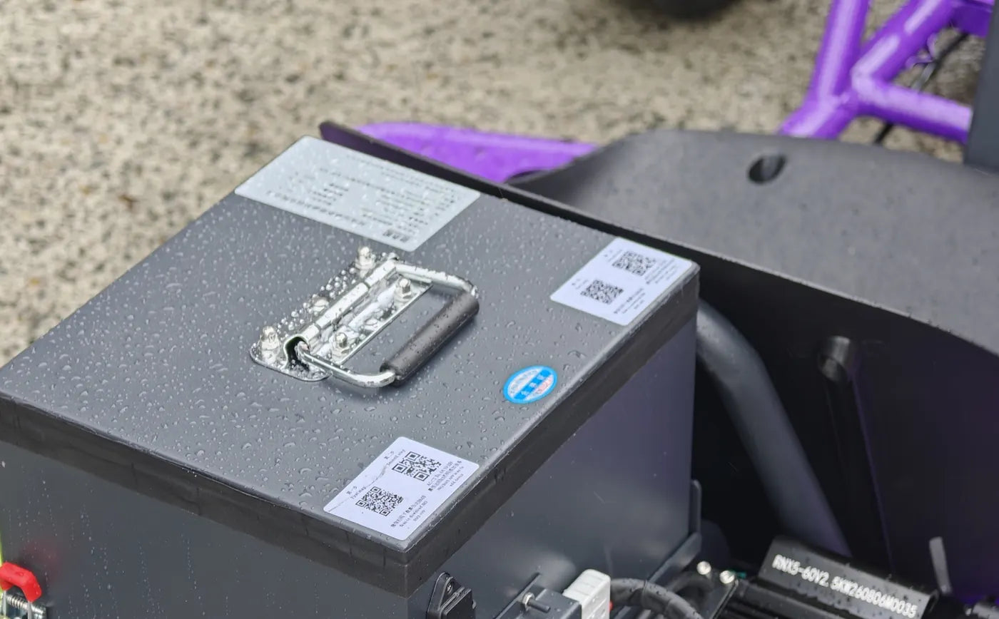 The 60V LiFePO4 battery box behind the seat, with its carry handle and the motor beside it