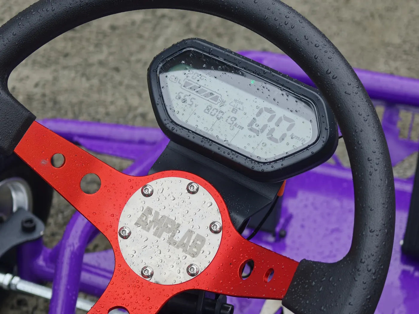 Close-up of the racing wheel with red spokes, AMPLAB centre cap and LCD dash